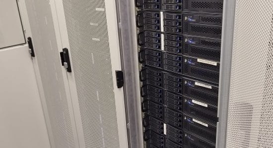 Couloir entre des baies de serveurs dans un datacenter, montrant des serveurs Chenbro RM217 dans une baie ouverte et un système de refroidissement optimisé au sol.