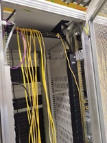 Image capturant l'arrière d'une baie serveur en pleine installation, montrant un switch connecté en haut de la baie et un PDU APC positionné sur le côté arrière, avec le câblage réseau en cours de mise en place. Cette vue détaille le processus méticuleux de montage et de connexion, essentiel pour garantir une distribution d'énergie fiable et une communication réseau efficace au sein du datacenter.