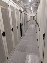 Vue d'un couloir central entre les baies de serveurs dans notre datacenter, mettant en évidence les grilles de ventilation au sol pour le refroidissement. Cette configuration illustre notre approche avancée pour maintenir une température stable et optimale, garantissant ainsi la performance et la sécurité des serveurs. Le refroidissement au sol joue un rôle clé dans l'efficacité énergétique et la fiabilité de nos installations.