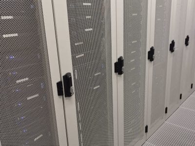 Rijen serverracks in het datacenter van StrictlyHosting.be, met transparante serverkasten waarin operationele apparatuur te zien is.