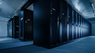 Image capturant l'intérieur d'un datacenter moderne, montrant trois rangées alignées de baies à serveurs. Cette vue d'ensemble illustre l'ampleur et l'organisation de notre infrastructure d'hébergement, mettant en évidence la capacité à héberger une large gamme de serveurs dans un environnement contrôlé et sécurisé. L'architecture et la disposition des baies reflètent notre engagement envers l'efficacité, la sécurité et la fiabilité des services d'hébergement.