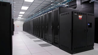 Vue sur une rangée de baies à serveurs dans une salle de datacenter, mettant en évidence le groupe de contrôle électrique et l'onduleur positionnés stratégiquement en début de la rangée. Cette disposition illustre l'importance de la gestion de l'énergie et la continuité de service, avec des systèmes d'alimentation sécurisés et fiables pour soutenir l'infrastructure critique du datacenter et garantir une opération ininterrompue.